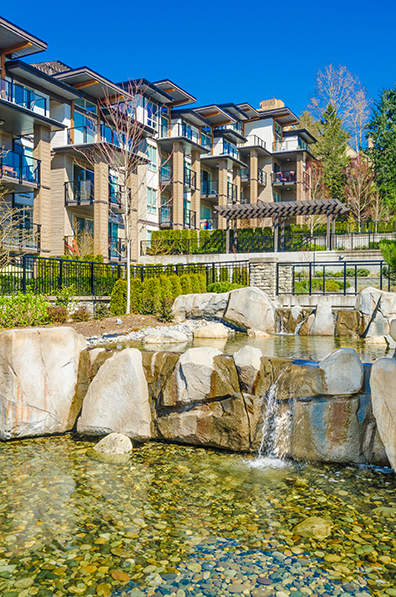 Multifamily apartment property with balconies overlooking a landscaped rock waterfall feature.