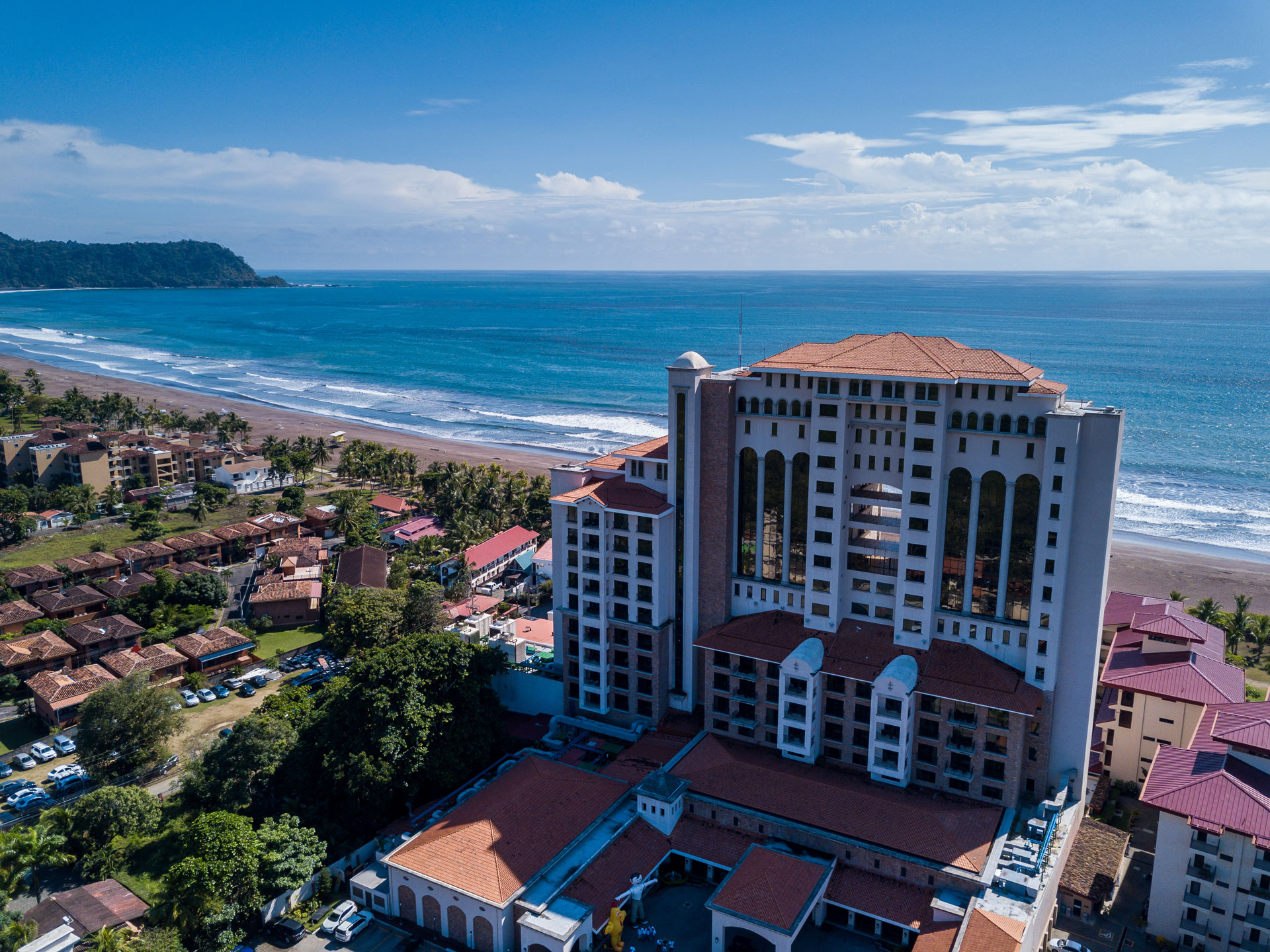 Aerial view of a high-rise beachfront hotel with surrounding coastal residential properties
