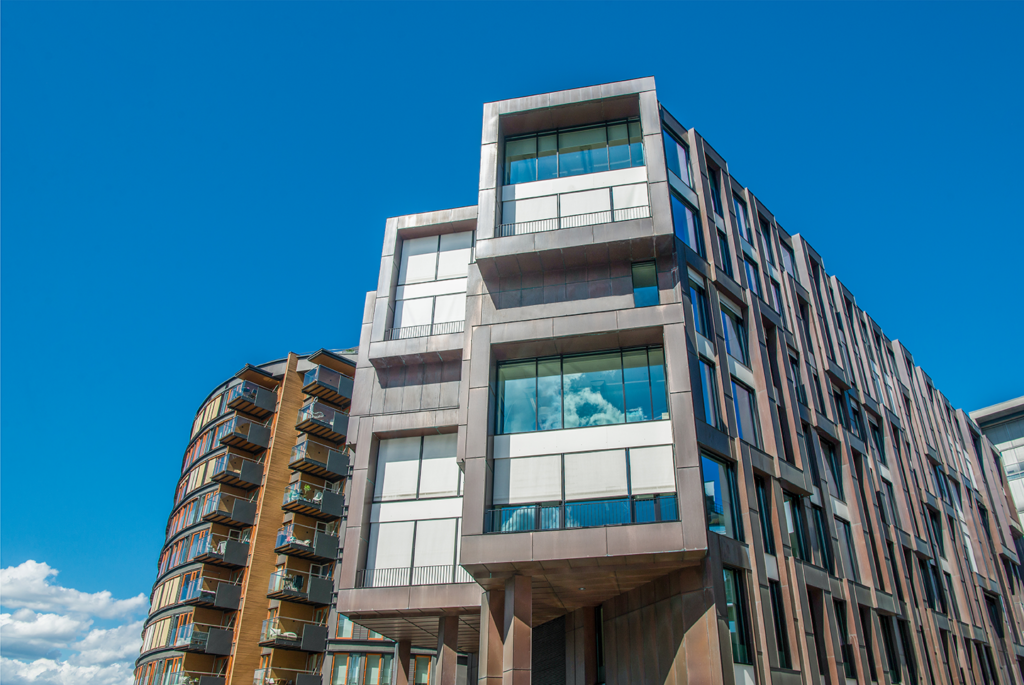 Exterior of a modern multifamily rental property with balconies, viewed from below against a clear blue sky.