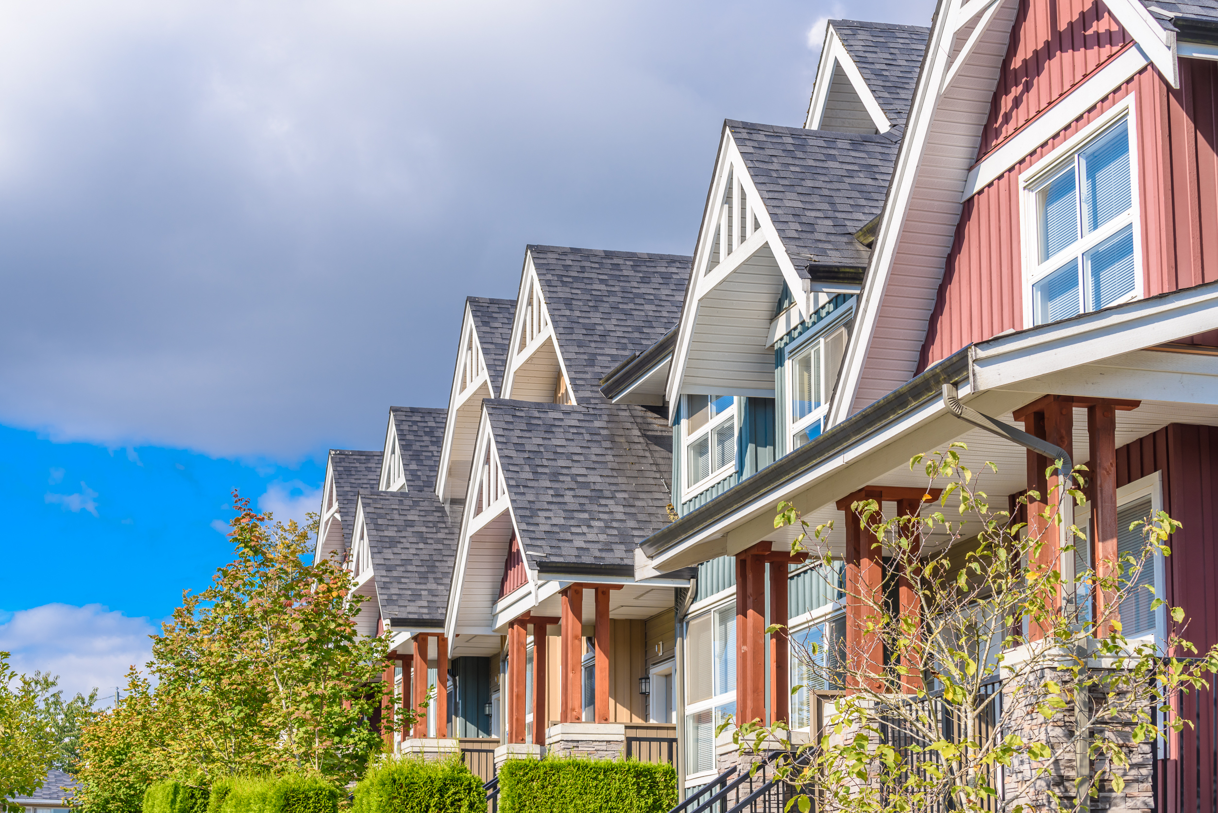 A row of colorful houses with green bushes in the front.